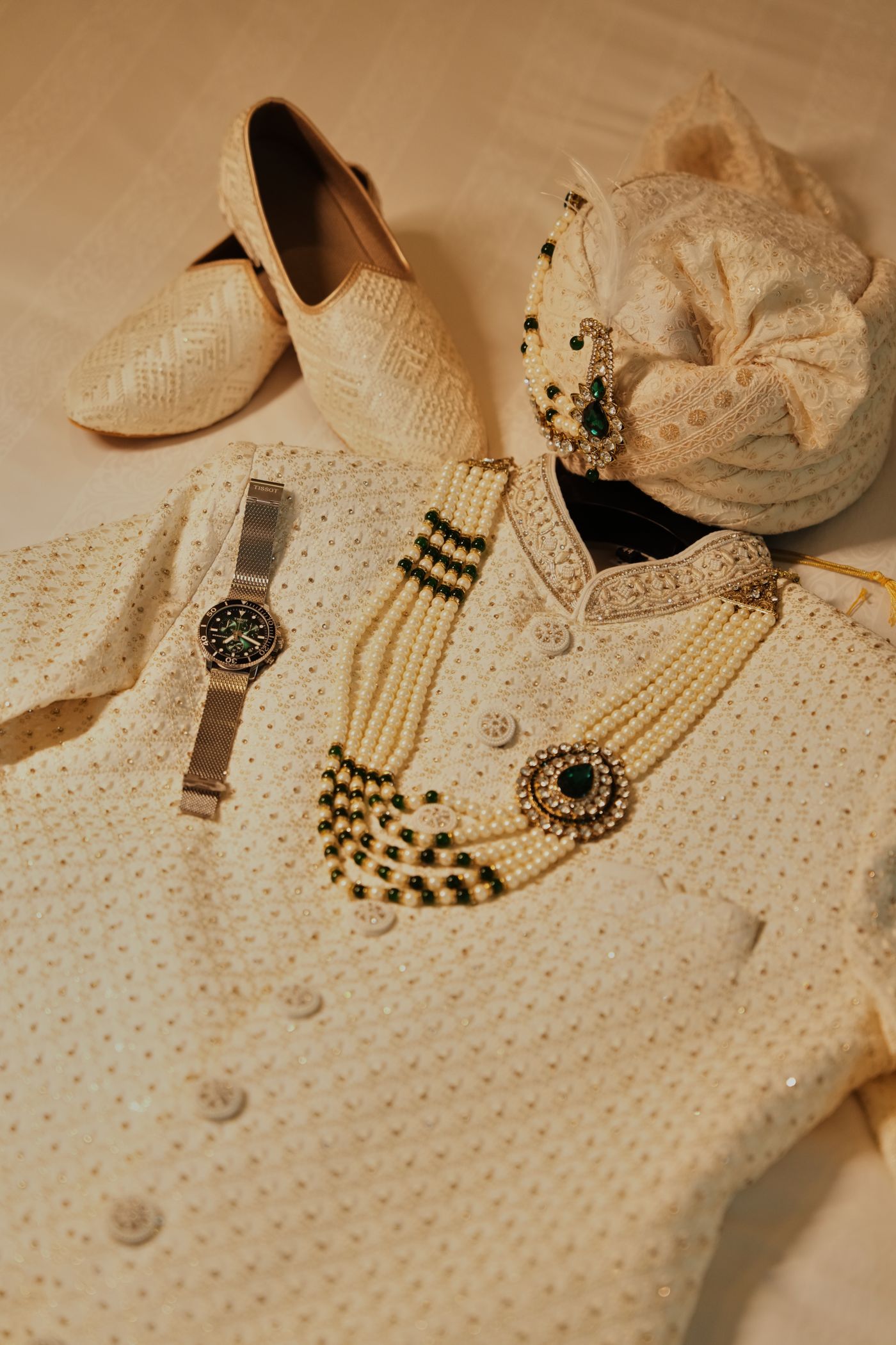 Complete dulha outfit laid out with sherwani, safa, mojari and mala