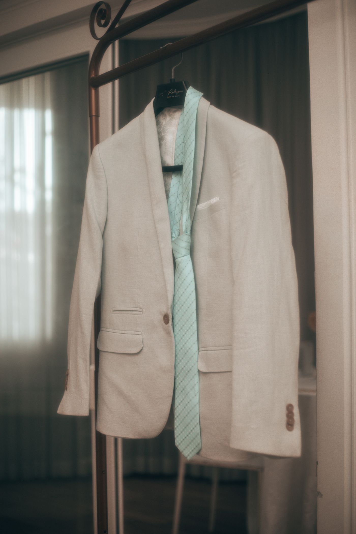 Cream linen jacket with mint tie on a hanging rail