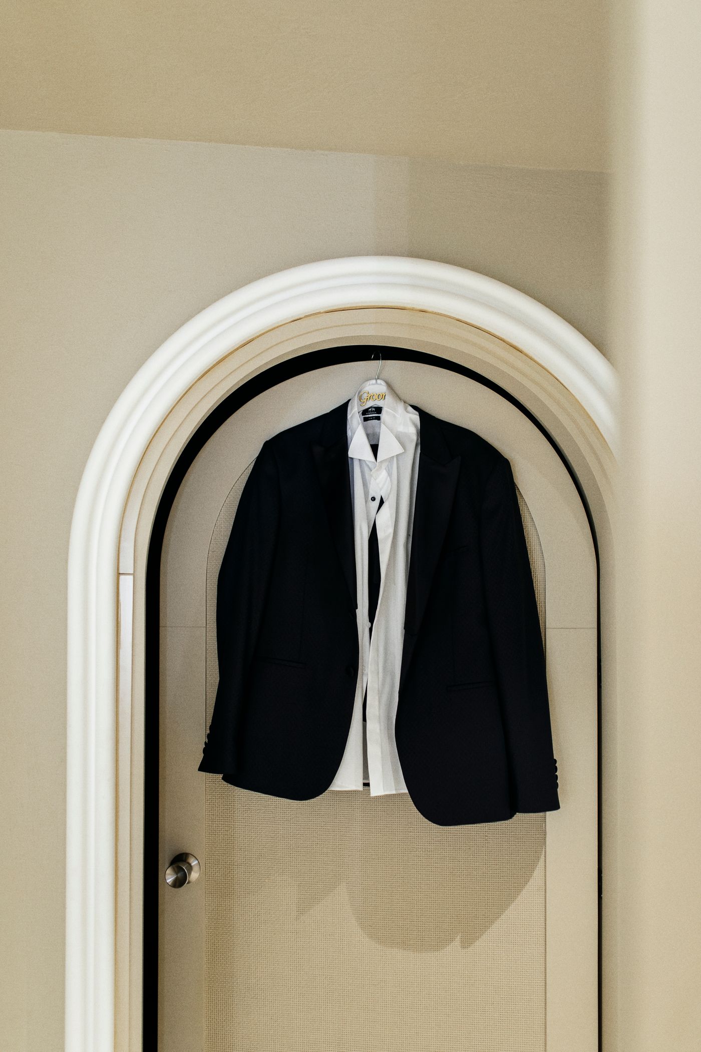 Black tuxedo jacket and white dress shirt on a hanger