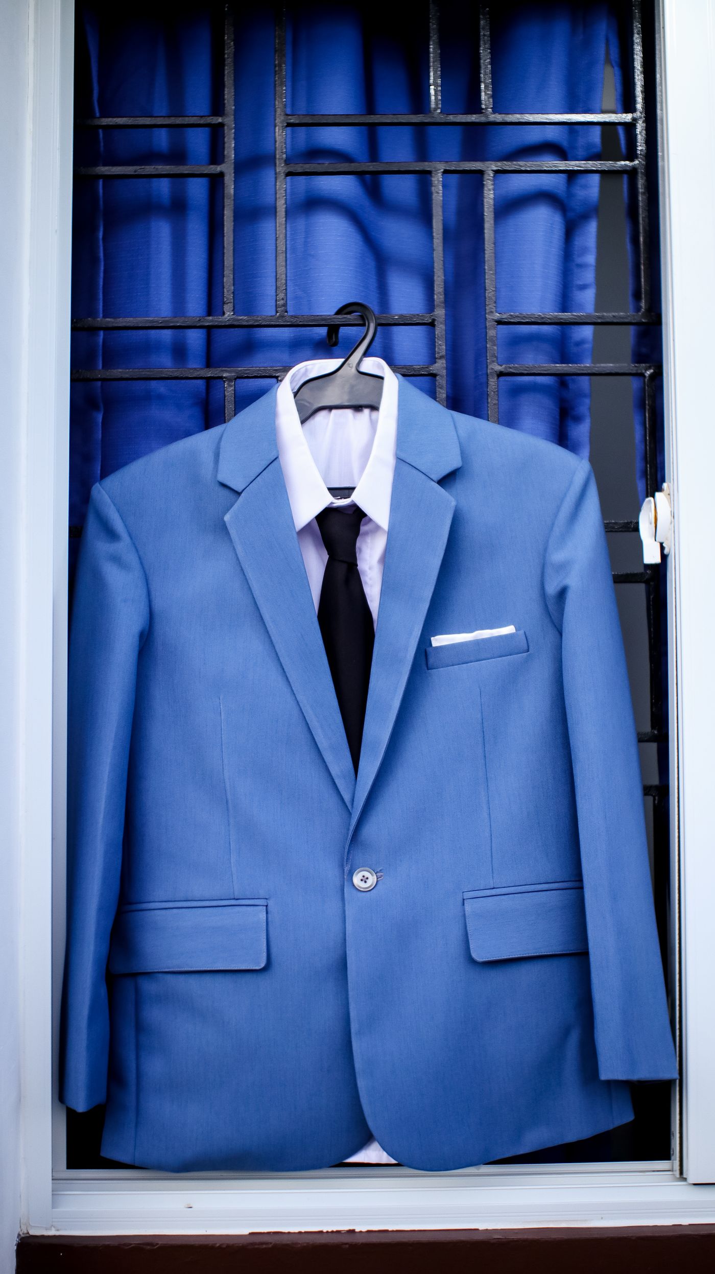 Blue coat pant with white shirt and black tie on a hanger