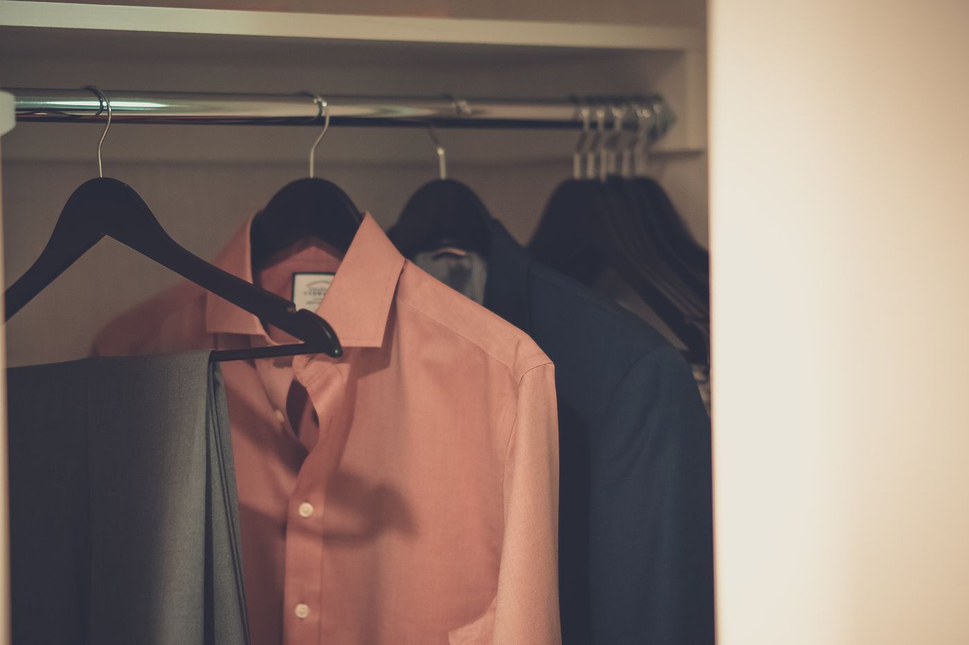 Formal shirts and suit trousers hanging in a wardrobe