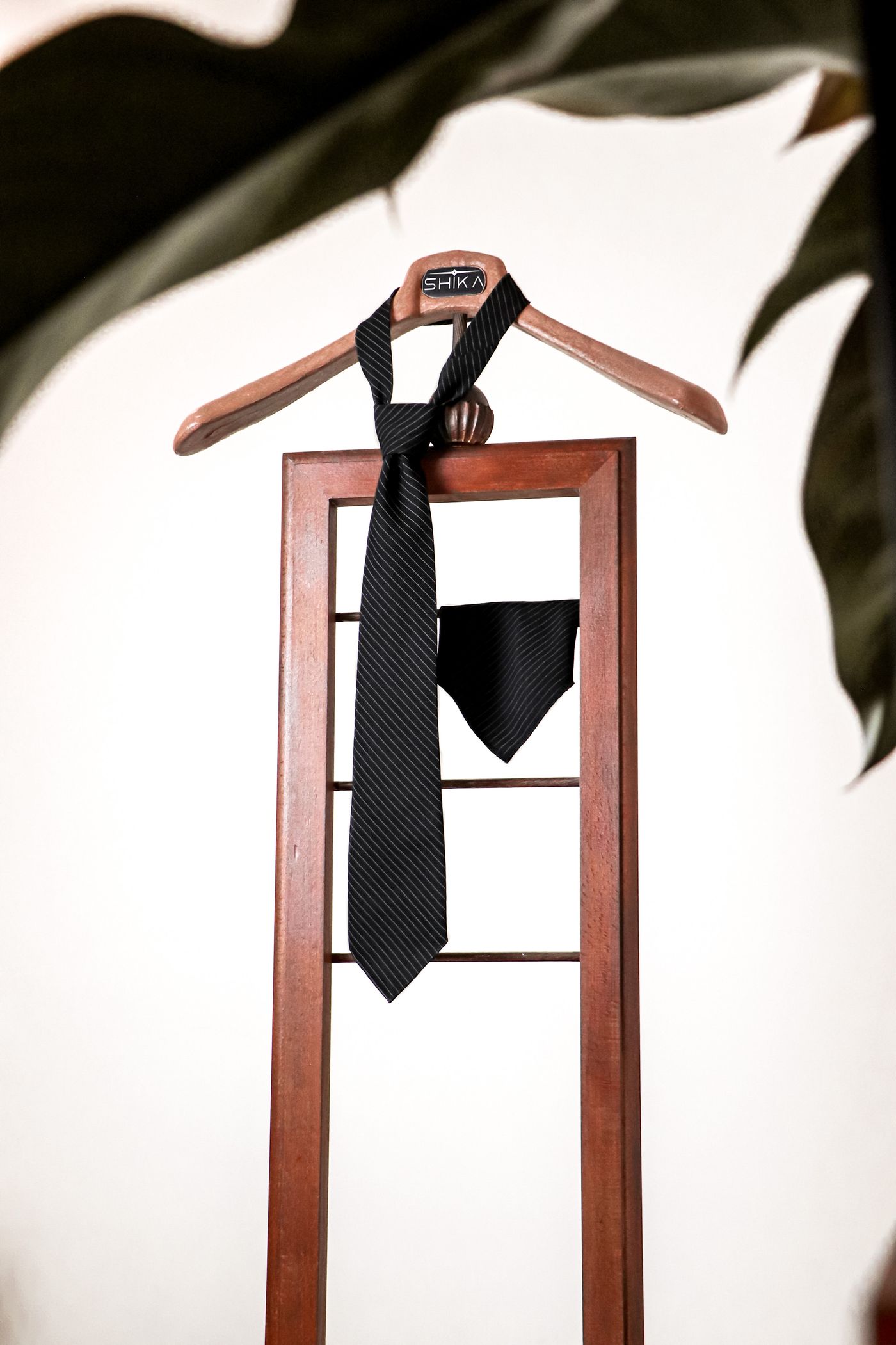 Black pinstripe necktie and matching pocket square on a valet stand