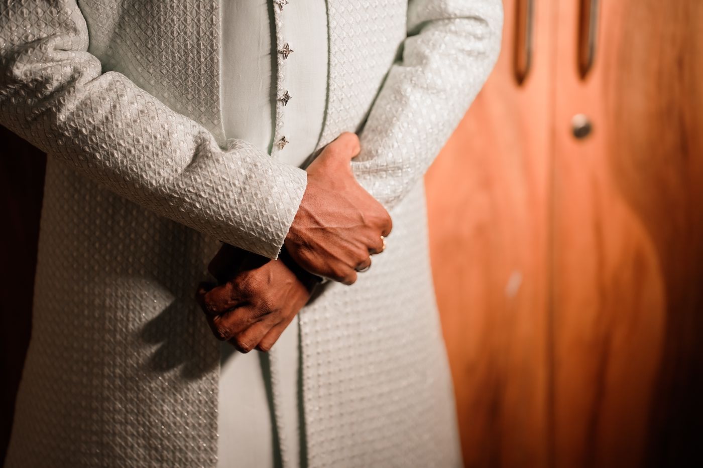 Close-up of white textured sherwani embroidery and placket buttons
