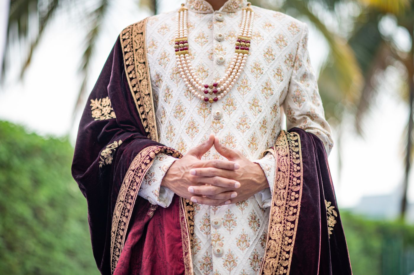 Cream sherwani with maroon velvet dupatta and layered pearl mala